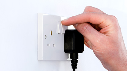 hand at power socket with plug