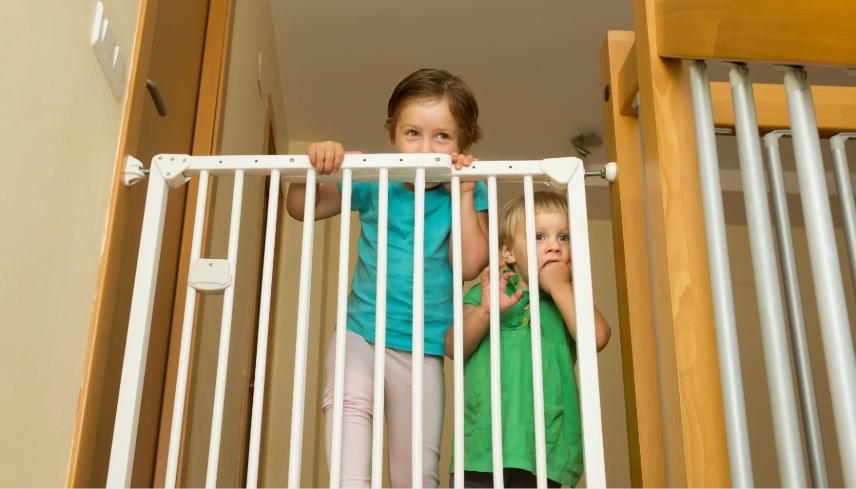 Two little girls approaching safety gate of  stairs at home